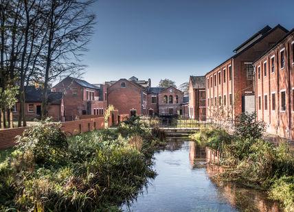 An image of a canal in a city, Two Tickets to a Guided Tour of Bombay Sapphire Distillery. Bombay Sapphire Distillery