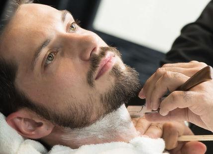 An image of a man getting his hair cut, Beard Grooming and Design Experience. Gentlemen's Tonic