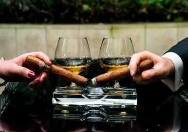 An image of two people holding glasses of wine, Cigar and Whisky Pairing Masterclass . Hotel Xenia, Autograph Collection 