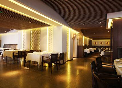 An image of a restaurant setting with tables and chairs, Five-Course Tasting Menu. Quilon