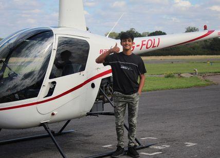 A  boy sitting to the helicopter before his flight