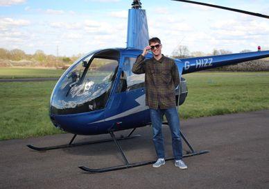 An image of Helicopter R22 and a man standing before his flight