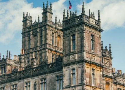 An image of a castle with a blue sky in the background, Highclere Castle. Highclere Castle
