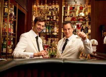 An image of two men with glass of whisky at the bar