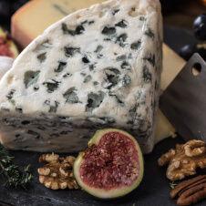 Blue cheese with figs and walnuts on a wooden board.