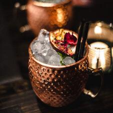 Two moscow mule mugs with ice and flowers.