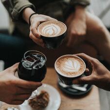A group of people toasting coffee in a coffee shop.