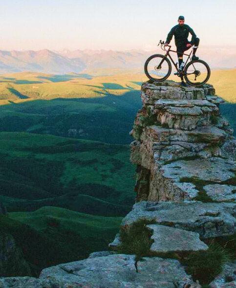 A man on a mountain bike standing on top of a cliff.