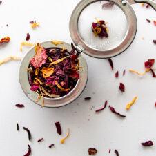 A tea strainer filled with dried flowers and leaves.