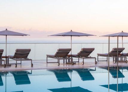 An image of a pool with chairs and umbrellas, Private hire of a Pershing Yacht at Ibiza. 7Pines Kempinski Ibiza Resort