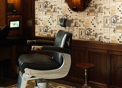 An image of a barber shop with a chair and a mirror, Traditional Haircut & Wet Shave. Alfred Dunhill