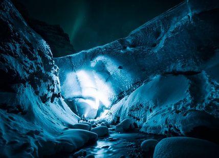 An image of a cave with a light shining in the cave, Bilbo’s newly discovered Blue Ice Cave tour. Arctic Adventures