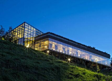 A glass building sits on top of a hill at night.