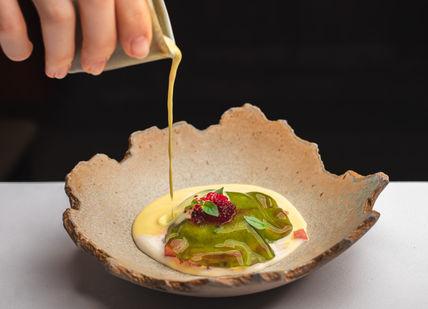 An image of a person pouring a sauce on a dish, Tasting Menu. Benares Restaurant and Bar