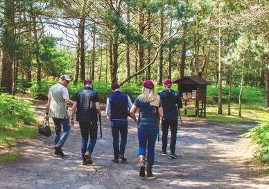 An image of a group of people walking in the woods, Clay Pigeon Shooting Near London for small group. Bisley Shooting Ground