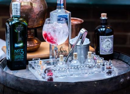 An image of a bar with alcohol and a bottle, The Gin & Tonic Experience. Chesterfield Mayfair Hotel