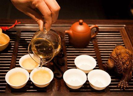 An image of a person pouring tea into cups, Gong Fu Cha Tea Tasting. The Chinese Tea Company