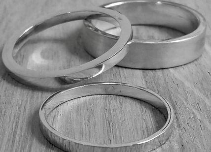 An image of two wedding rings on a wooden table, Jewellery Making Class: Silver Ring. Collette Dawn