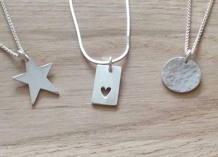 An image of three silver necklaces on a wooden table, Silver Charm Jewellery Making Class. Collette Dawn