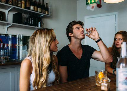 An image of a man drinking a drink with two women, The Ginstitute Experience. The Distillery