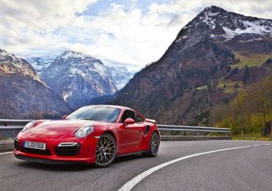 An image of a red porsche sports car driving down a mountain road, The Klausen Pass Dolder Grand The Restaurant. The Dolder Grand The Restaurant