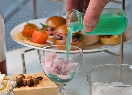 An image of a person pouring something into a glass, Science-Inspired Cocktail Afternoon Tea. The Drawing Room at The Ampersand Hotel