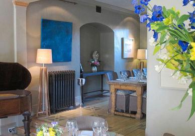 An image of a living room with a piano and flowers, Four-Course Dinner. The Dysart Petersham