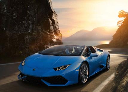 An image of a blue lamb car driving down a mountain road, One day hire of Lamborghini Huracan or Ferrari 488 Spider. Edel & Stark