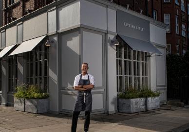An image of a man standing outside of a restaurant, Elystan Street. Elystan Street