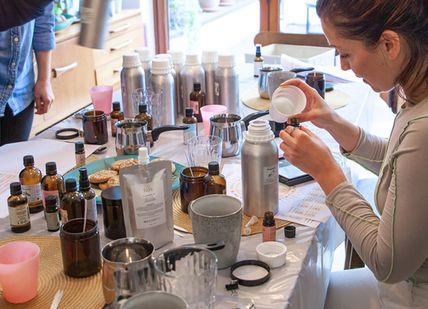 An image of a woman pouring something into a cup, Luxury Vegan Candle Making Workshop. Fais HQ