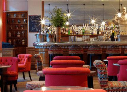 An image of a bar with red chairs, Luxury Cinema and Dining. Firmdale Hotels