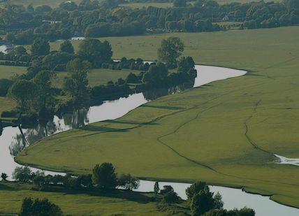 An image of a river running through a green field, Picnic Cruise. The Folly Restaurant