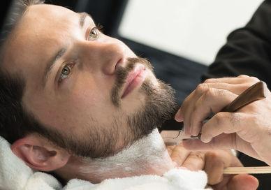 An image of a man getting his hair cut, Beard Grooming and Design Experience. Gentlemen's Tonic