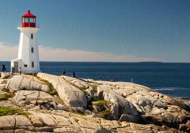 A lighthouse sits on top of a rocky cliff.