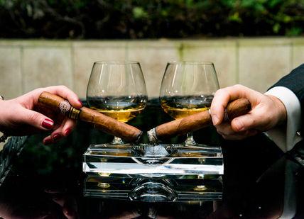 An image of two people holding glasses of wine, Cigar and Whisky Pairing Masterclass . Hotel Xenia, Autograph Collection 