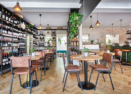 An image of a restaurant with wooden tables and chairs, Islington, London. Humble Grape