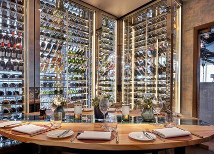 A dining room with wine racks and a table.