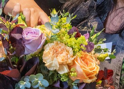 An image of a woman holding a bunch of flowers, Hand-Tied Bouquet Workshop. McQueens