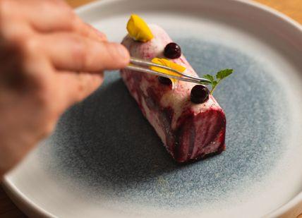 An image of a person eating a piece of food, Six-Course Tasting Menu. Mere Restaurant