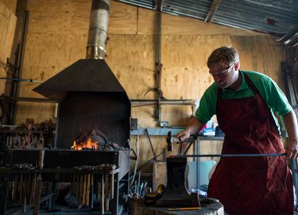 An image of a man working in a wood shop, Blacksmithing Taster Experience. Now Strike Archery
