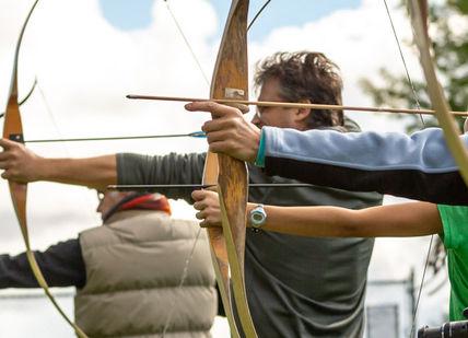 An image of a man and woman shooting arrows, Longbow Archery Experience. Now Strike Archery