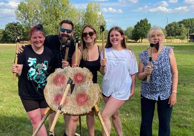 An image of four girls standing in a field, Viking Axe Throwing Session. Now Strike Archery