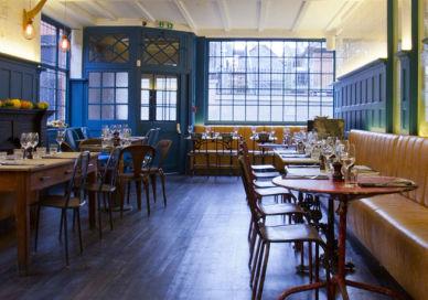 An image of a restaurant with many tables, British craft beer tasting and bar snacks. Parlour