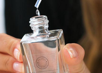 An image of a woman holding a perfume bottle, Platinum Perfume Experience. The Perfume Studio