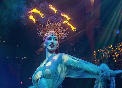 An image of a woman in a costume with fire on her head, VIP Entry Tickets and Dinner. Proud Cabaret