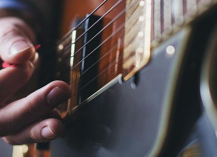 An image of a person playing a guitar, Private music lesson series. Rhythm Room Music School