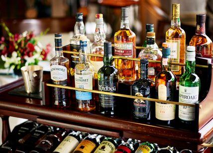 An image of a bar with alcohol bottles, Whisky Tasting and Sharing Platters. The Rubens at the Palace - The New York Bar