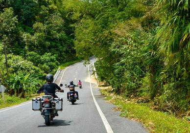 An image of a man riding a motorcycle down a road, Private Ten-Day Motorcycle Tour. Samadhi Retreats