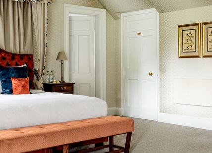 An image of a bedroom with a bed and a dresser, Scottish Golf Getaway. SCHLOSS Roxburghe Hotel