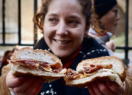 An image of a woman eating a sandwich, London Bridge Secret Food Tour. Secret Food Tours